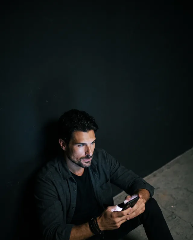 Retrato editorial dark criado no Studio da Tizze: homem com celular contra parede escura